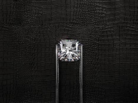 Cut Beautiful diamond held by tweezers, on a black leather background