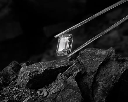 Cut Beautiful diamond held by tweezers on black coal background