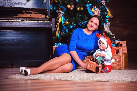 A cheerful mother and her child are joyfully enjoying a precious holiday moment together by the festive tree