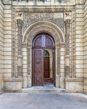 The beautifully carved wooden door of Beylar Mosque in baku, Azerbaijan, features ornate decorations and is framed by intricately designed stonework, highlighting artistic craftsmanship