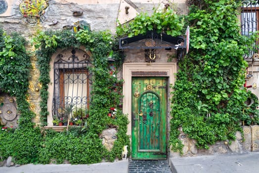 A striking green door framed by lush greenery and ornate windows enhances the historic beauty of Icherisheher, Baku. The natural elements add life to the traditional architecture