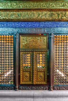Elaborately decorated tomb of Ukeyma Khanum, a significant historical figure in Azerbaijan, adorned with golden trimmings and situated within a latticework enclosure at the Bibi-Heybat Mosque in Baku