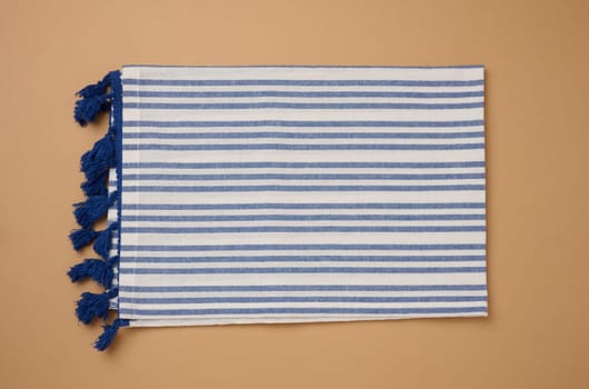 Folded linen striped kitchen towel on brown background, top view