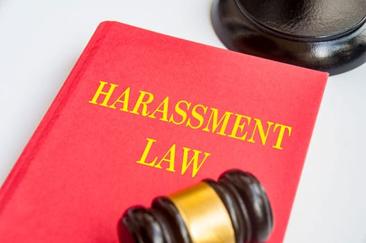 Side view of Harassment Law book with gavel on white background. Zero harassment concept.