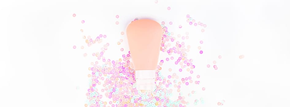 Cosmetic cream lotion tube on white pearl pastel confetti sparkles background with copy space. Creative conceptual top view flat lay backdrop for your beauty blog text design
