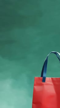 Red shopping bag with blue handles against a green background, ideal for marketing and branding with copy space. Black Friday sale concept with place for text.