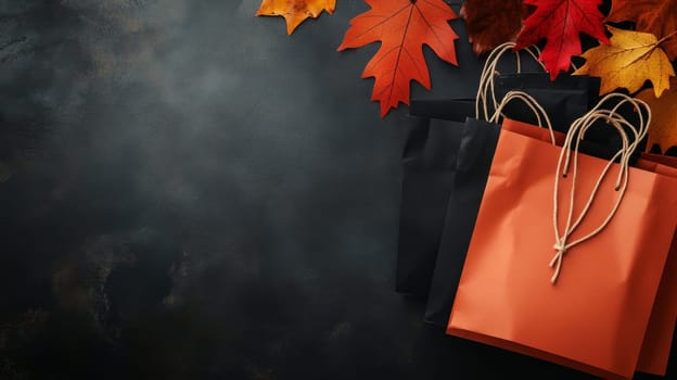 Black and orange shopping bags with autumn leaves on a dark textured background, offering copy space. Black Friday sale concept with empty place for text.