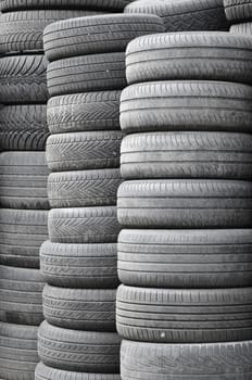 Old used tires stacked with high piles in secondary car parts shop garage close up