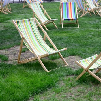 Chaise lounges on a lawn. Rest in the festival, on vacation. Garden sunbeds on green grass. Garden bed for sunbathing and rest. Summer chair