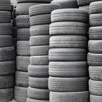 Old used tires stacked with high piles in secondary car parts shop garage close up