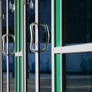 Chrome door handle and glass of modern aluminium door outside the office building