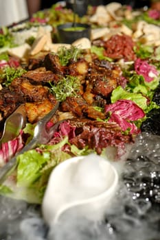 A banquet table is adorned with an extravagant display of grilled meats, vibrant greens, and colorful garnishes, creating an impressive feast perfect for a festive celebration or special occasion.