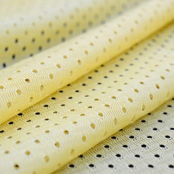 Yellow mesh sport wear fabric textile pattern background. Yellow color football jersey clothing fabric texture sports wear. Breathable porous poriferous material air ventilation with small holes