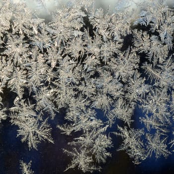 Snowflakes frost rime macro on window glass pane. Colorful ice on the window surface, natural background texture