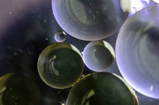 Extreme close up of oil bubbles on water surface.