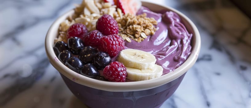 A close-up photo of an acai bowl filled with granola, bananas, raspberries, and blueberries on a light wooden table