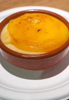 Catalan cream served in a clay bowl over wooden background. Selective focus
