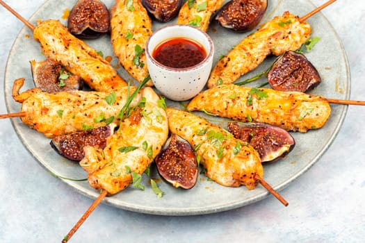 Tasty and colorful chicken meat skewers with figs on a plate. Delicious summer lunch.