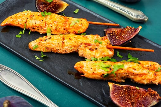 Tasty and colorful chicken meat skewers with figs on a plate. Delicious summer lunch.