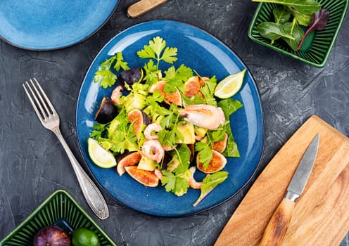 Platter of green salad with figs and figs. Seafood salad on a concrete kitchen table.