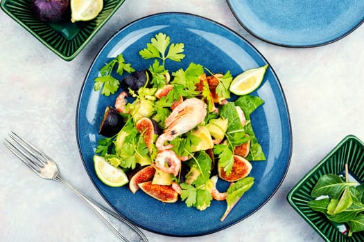 Platter of green salad with figs and figs. Seafood salad on a concrete kitchen table.