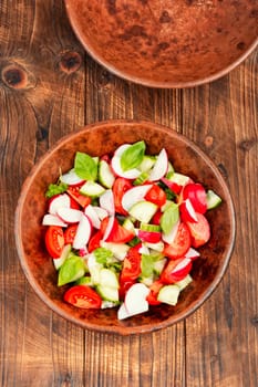 Healthy vegetable salad of fresh tomato, cucumber, radishes on plate. Space for text.