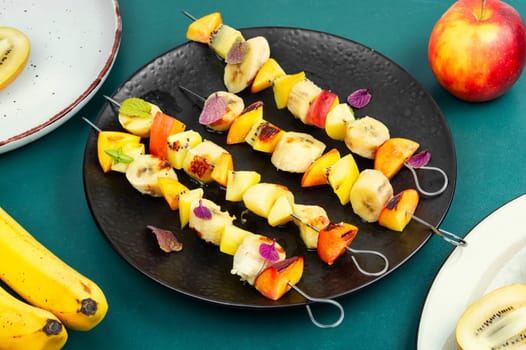 Grilled fruits on iron skewers. Fruit kebabs. Grilled fruit