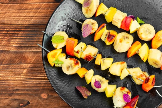 Grilled fruits on iron skewers. Fruit kebabs. Grilled fruit