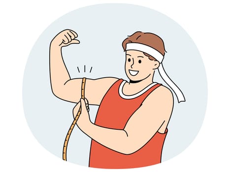 Strong man shows biceps and uses measuring tape to check size of muscles on arm. Strong guy in sportswear boasts about size of biceps and recommends doing bodybuilding or arm wrestling