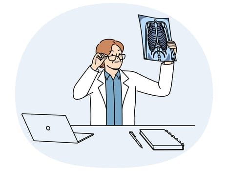 Woman doctor holding x-ray picture of sick conducting medical examination of patient with lung problems. Doctor examines x-ray film trying to diagnose person who asked for help from hospital staff