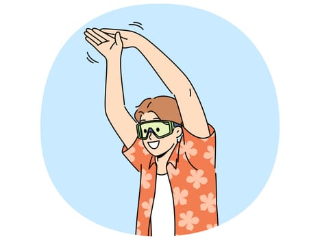Man tourist stands in pose of swimmer wanting to dive into pool or sea during summer vacation. Young happy guy in goggles for swimming and summer shirt getting ready to jump in sea water