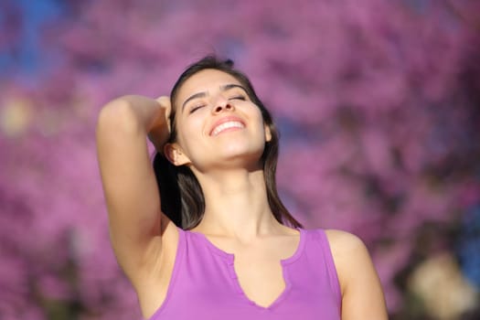 Happy woman smiling and touching hair in a violet park