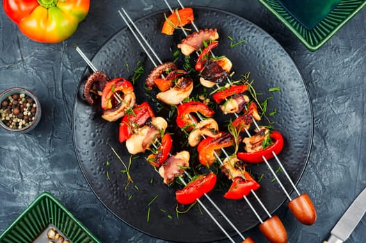 Succulent grilled octopus tentacles with bell pepper on a concrete kitchen table.