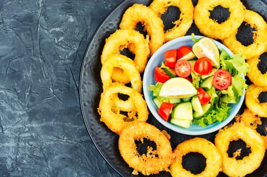 Delicious Fried squid rings and fresh vegetable salad. Close up.
