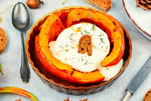 Halved orange pumpkin, baking. Pumpkin or squash baked with camembert.