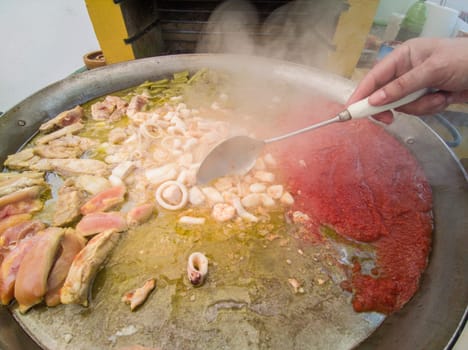Preparation of mixed valencian paella. Outdoor garden background