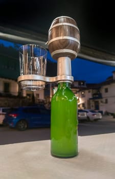 Bottle equipped wiith electric natural asturian cider pourer. Terrace restaurant at night