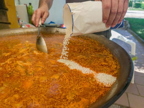 Preparation of mixed valencian paella. Outdoor garden background