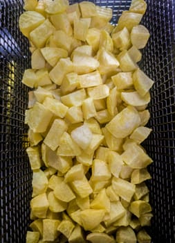Basket of dices potatoes in the deep fryer of a restaurant kitchen. Overhead view