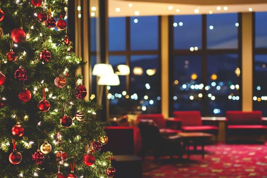 Colorful ornaments adorn a Christmas tree beside a warmly lit lobby filled with comfortable seating and twinkling lights.