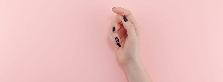 Stylish trendy female black manicure. Beautiful young woman's hands on millennial pink pastel background. Beauty and SPA concept. Banner Template for feminine blog social media