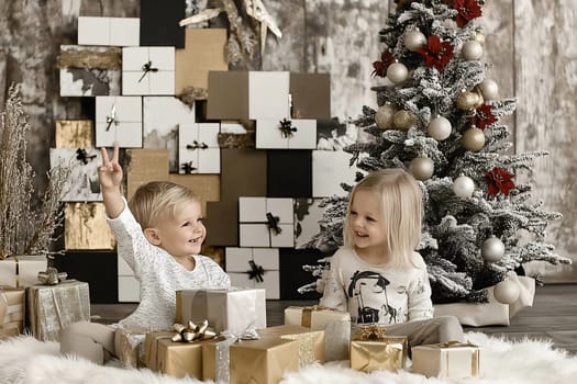 Two cheerful children are playing with gifts and enjoying the festive decorations beneath a Christmas tree in a warm, inviting space.