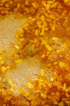 full-frame background and texture of sliced yellow apples boiling in syrup during confiture cooking.
