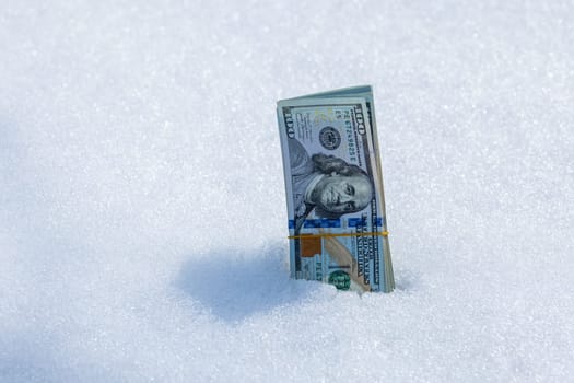 A bundle of cash lying on a snowy surface, vividly illustrating themes of financial waste and missed opportunities