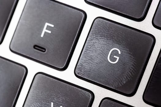 keyboard of famous silver colored laptop with fingerprints, closeup
