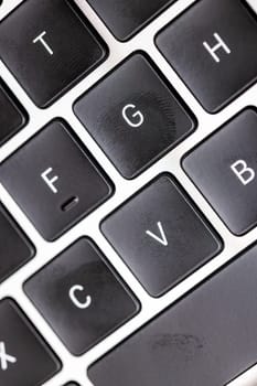 keyboard of famous silver colored laptop with fingerprints, closeup