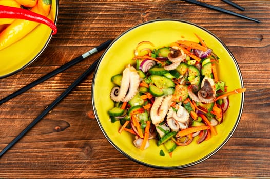 Salad of squid tentacles or calamari and vegetables in a bowl on rustic wooden table.