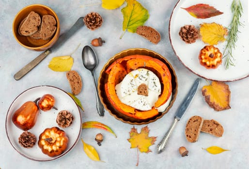 Autumn pumpkin baked with camembert cheese on a rustic wooden table. Healthy food.