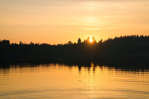 Sunset with warm colors on a Swedish lake in Smalland. Romantic evening atmosphere. Scandinavian nature