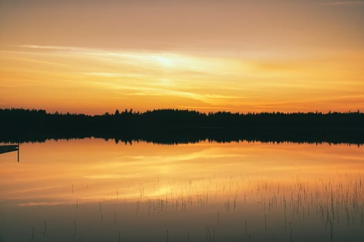 Sunset with warm colors on a Swedish lake in Smalland. Romantic evening atmosphere. Scandinavian nature